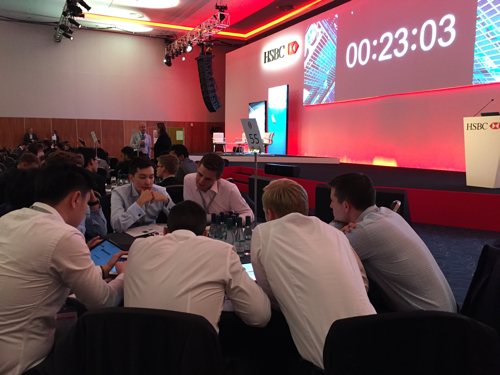 Graduate recruits around a conference table taking part in a banking sim