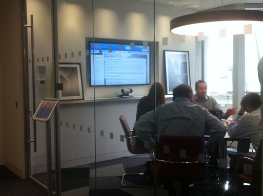 Team members around a table with simulation content on large wall screen behind them