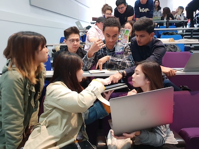 Students discussing simulation decisions in lecture theatre