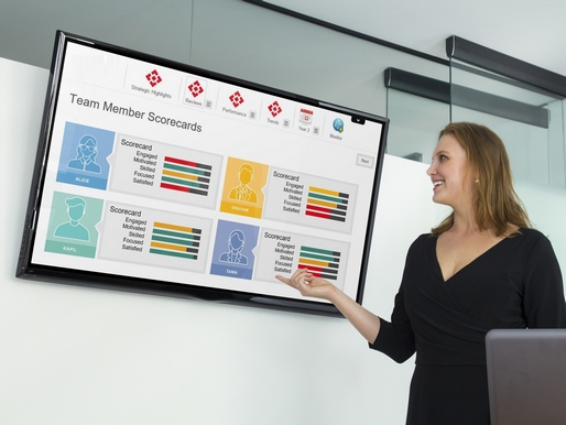 Facilitator pointing at leadership sim results page with scorecards of fictional team members